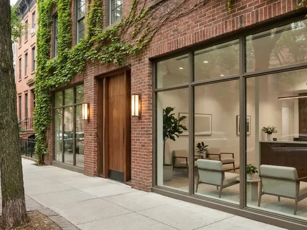 Modern Louisville dental practice entrance in a converted brick building with warm lighting and tree-lined Highlands street