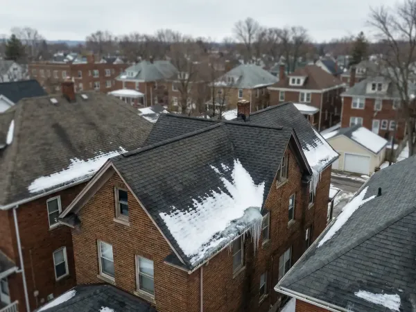 Professional roofing contractor inspecting a snow-covered roof in Rochester, NY