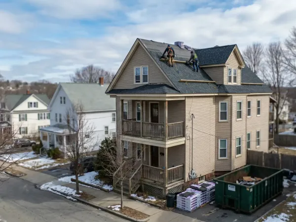 Professional roofing crew installing architectural shingles on a Worcester, MA triple-decker home