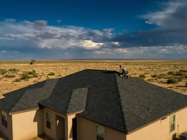 Professional roofing crew installing architectural shingles on a residential home in Midland, TX under a West Texas sky