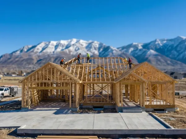 Construction contractor reviewing plans in a newly finished basement in Provo, UT, with the Wasatch Mountains visible through the egress window