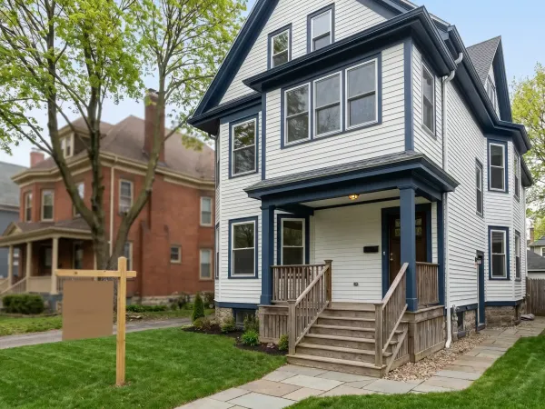 Real estate agent showing a classic New Bedford, MA triple-decker property to first-time homebuyers on a sunny spring afternoon