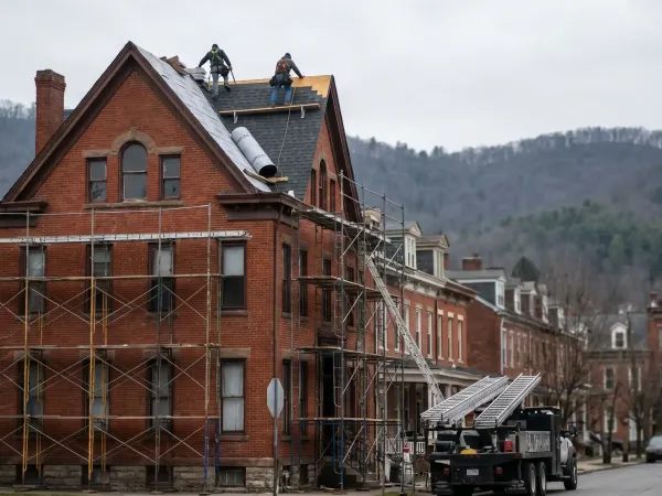 Roofing crew replacing a steep-pitched roof on a Victorian-era brick home in a Scranton, PA rowhouse neighborhood